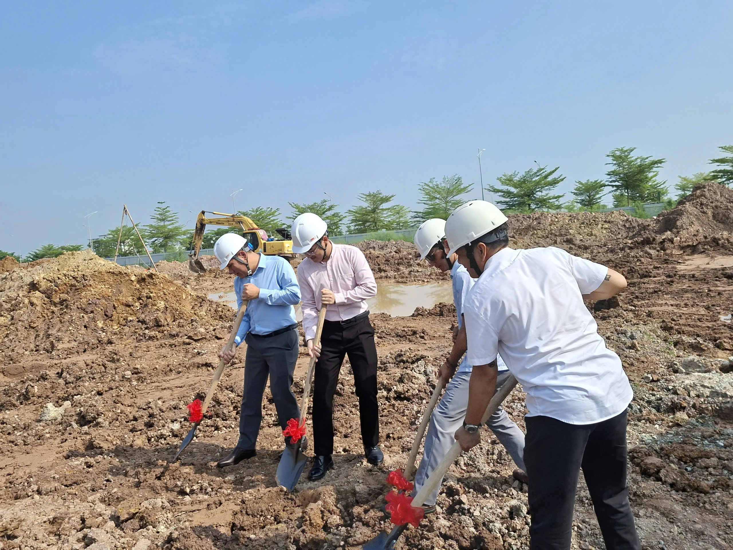 Các thành viên đội ngũ đội mũ bảo hộ, tham gia động thổ tại công trường